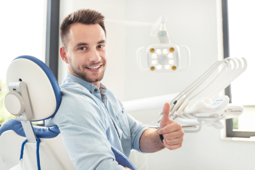 young man at the dentist giving his thumbs up